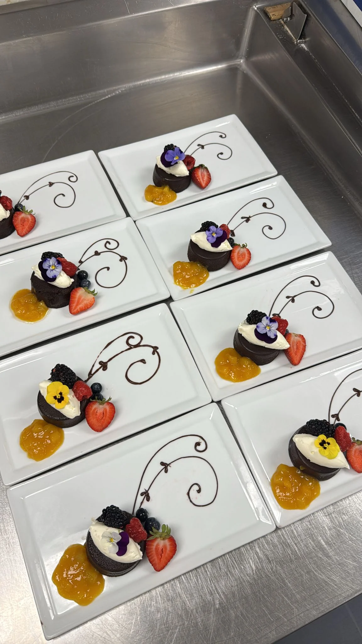 Chocolate Cups — dark chocolate cups with passion fruit curd, mixed berries and edible flowers, plated for service